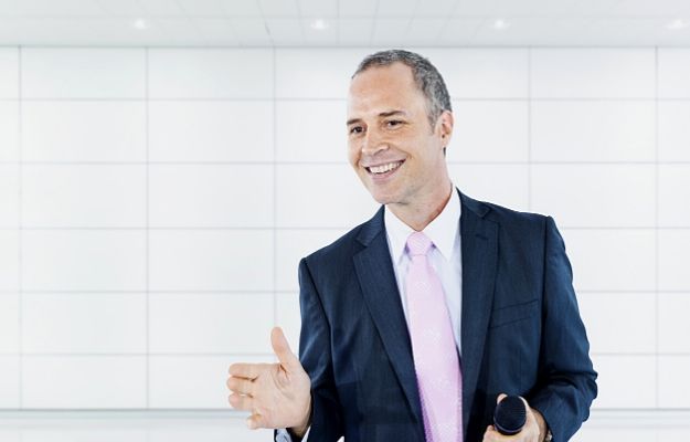 Business man smiling and holding microphone | Inspire a Great Culture