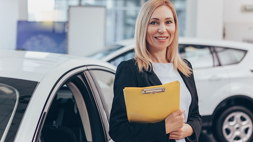 Professional car dealer posing proudly at auto showroom