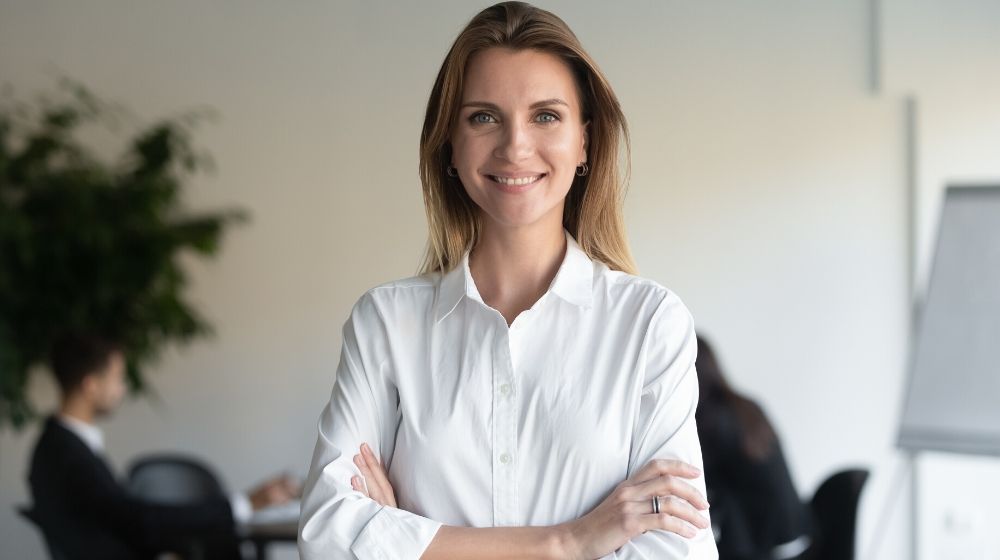 Smiling beautiful female professional manager standing with arms crossed looking at camera