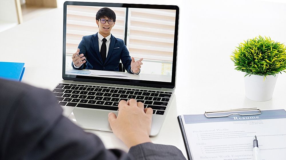 a business man having online interview on computer | Feature img | 9 Interview Questions To Ask Your Next Sales Rep