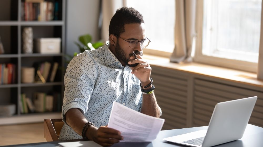 a sale man holding document looking at the computer