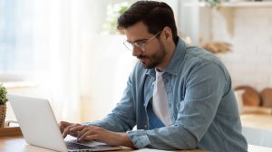 bearded man with glasses working focused on his computer