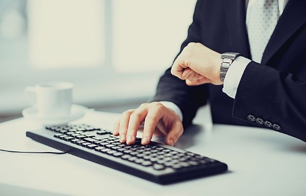 business man checking his watch while working on computer | Not Responding in a Timely Manner