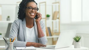 Office Girl Having Phone Conversation With Client Sitting At Laptop In Modern Office