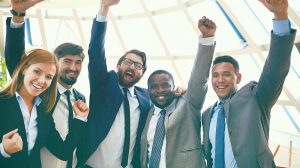 Group of ecstatic business partners looking at camera with raised arms