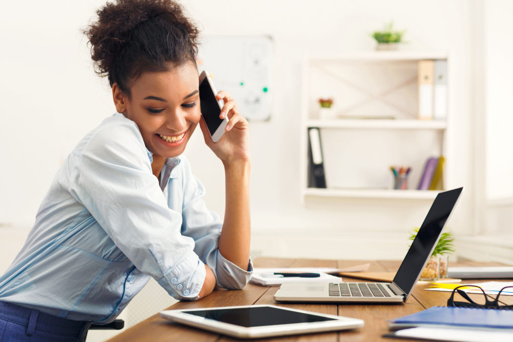 Happy african-american business woman talking on mobile at office | Ice Breakers Sales Reps Can Use to Ramp Up Conversions | Ice Breaker Sales | building activities