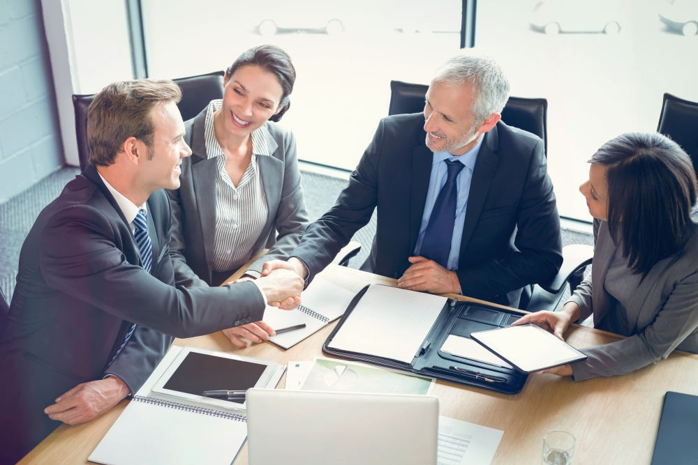 High angle view of businessmen shaking hands in conference room at office | Ways To Increase Sales Productivity | sales enablement