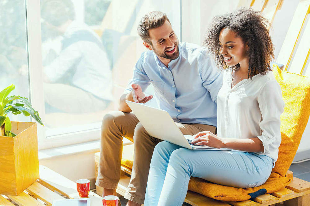 Smiling young African woman working on laptop while man sitting near her | How To Use The Law of Reciprocity When Social Selling Checklist | rule of reciprocation