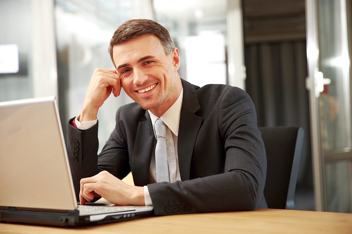 Smiling businessman facing laptop | Best Products for Sales