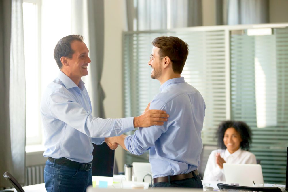 Smiling middle-aged ceo promoting motivating worker shaking hands congratulating | Employee Engagement Ideas During Change With Sharlene Dozois at Cision | improve employee
