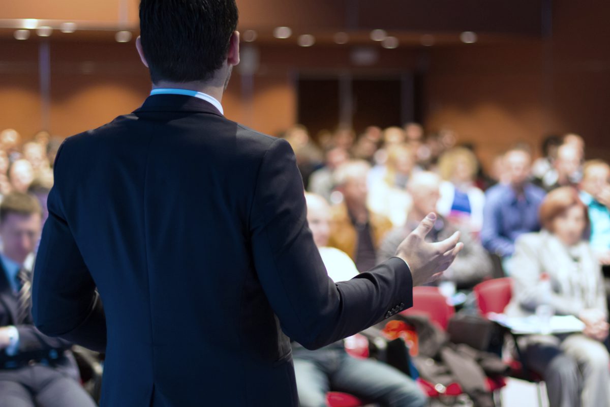 speaker at a business conference talking to his audience | Cross Selling And How It Can Drive Growth and Profitability To Your Business | cross-selling | what is cross-selling in retail